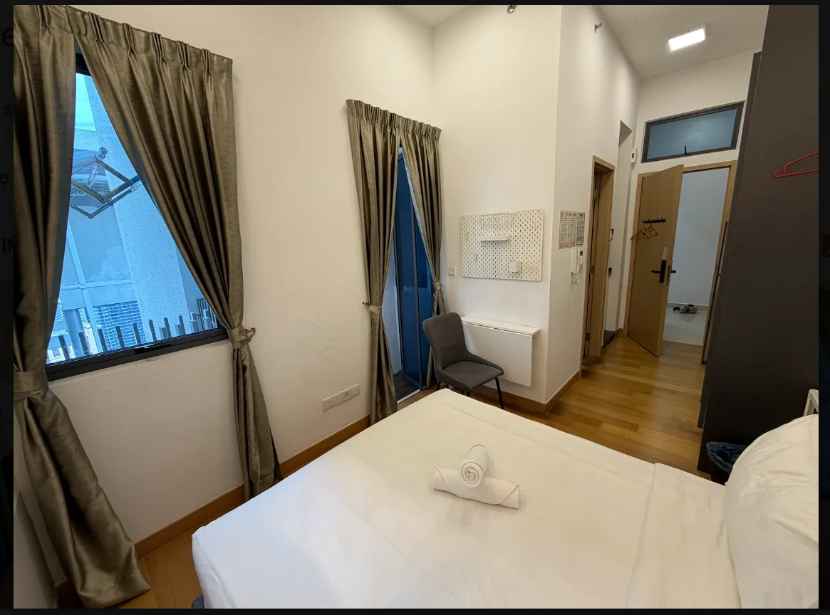 Bedroom features: queen-size bed with white bedding, wooden flooring, two large windows with sheer curtains, grey curtains, wall-mounted mirror, chair, wall-mounted coat rack, light fixture on ceiling, white walls, air conditioning unit, built-in wardrobe; style: modern; view: city.